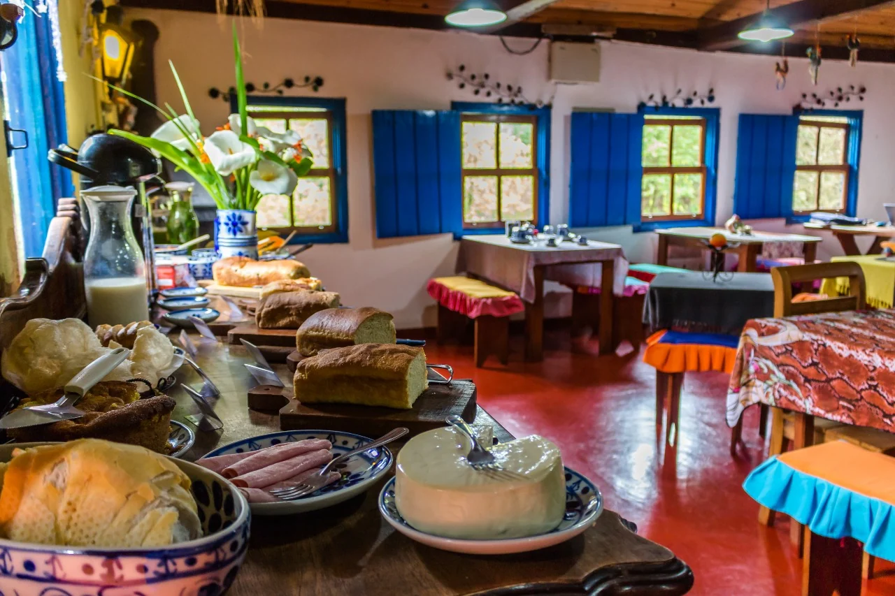 Mesa de café da manhã com pães e queijos no salão de janelas azuis