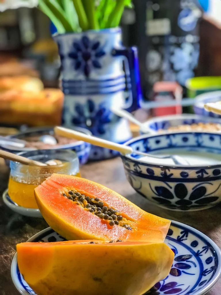 Mamão, geleia e louças azuis na mesa do café da manhã