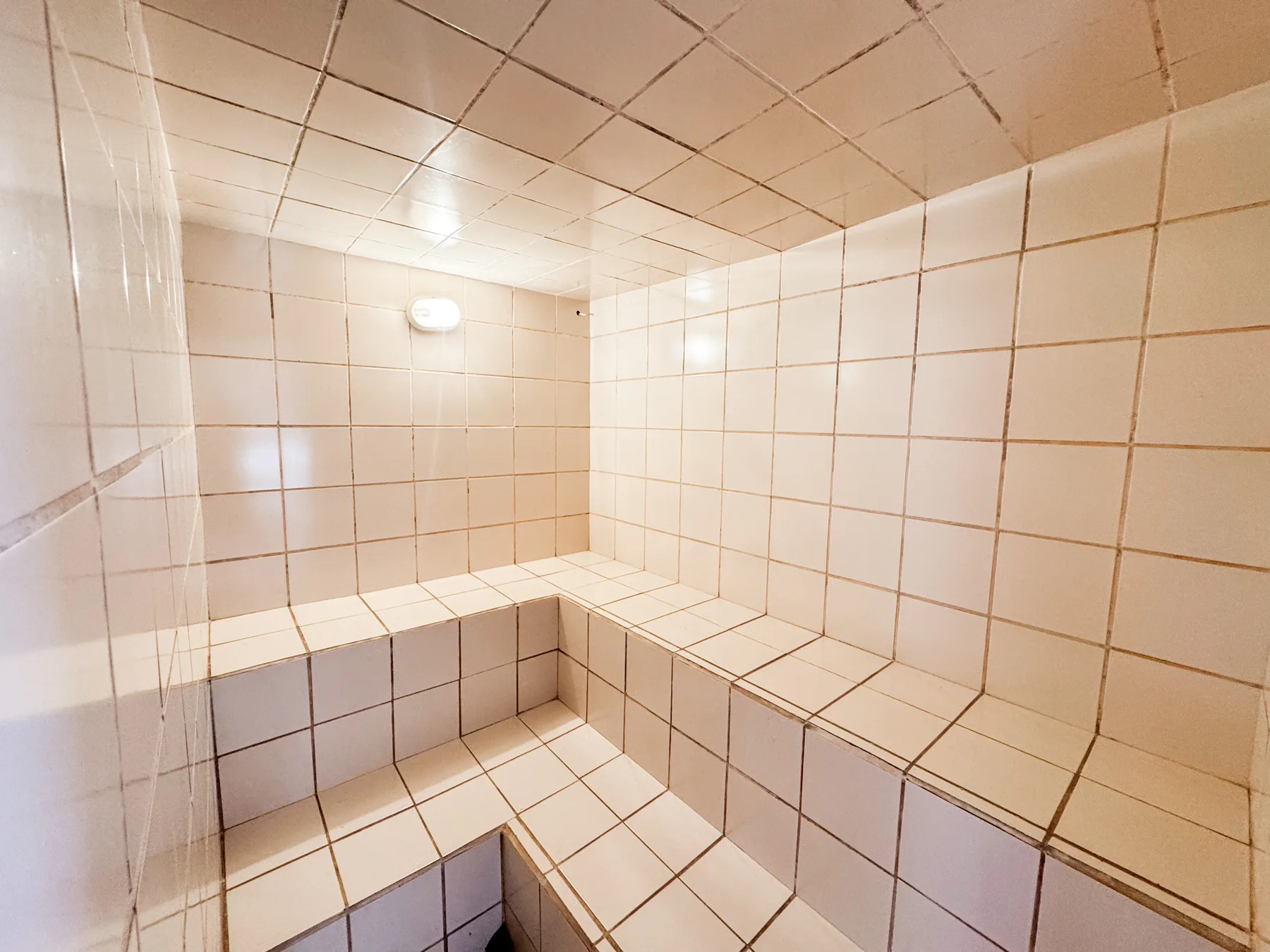 Sauna úmida com bancos e paredes revestidos de azulejos