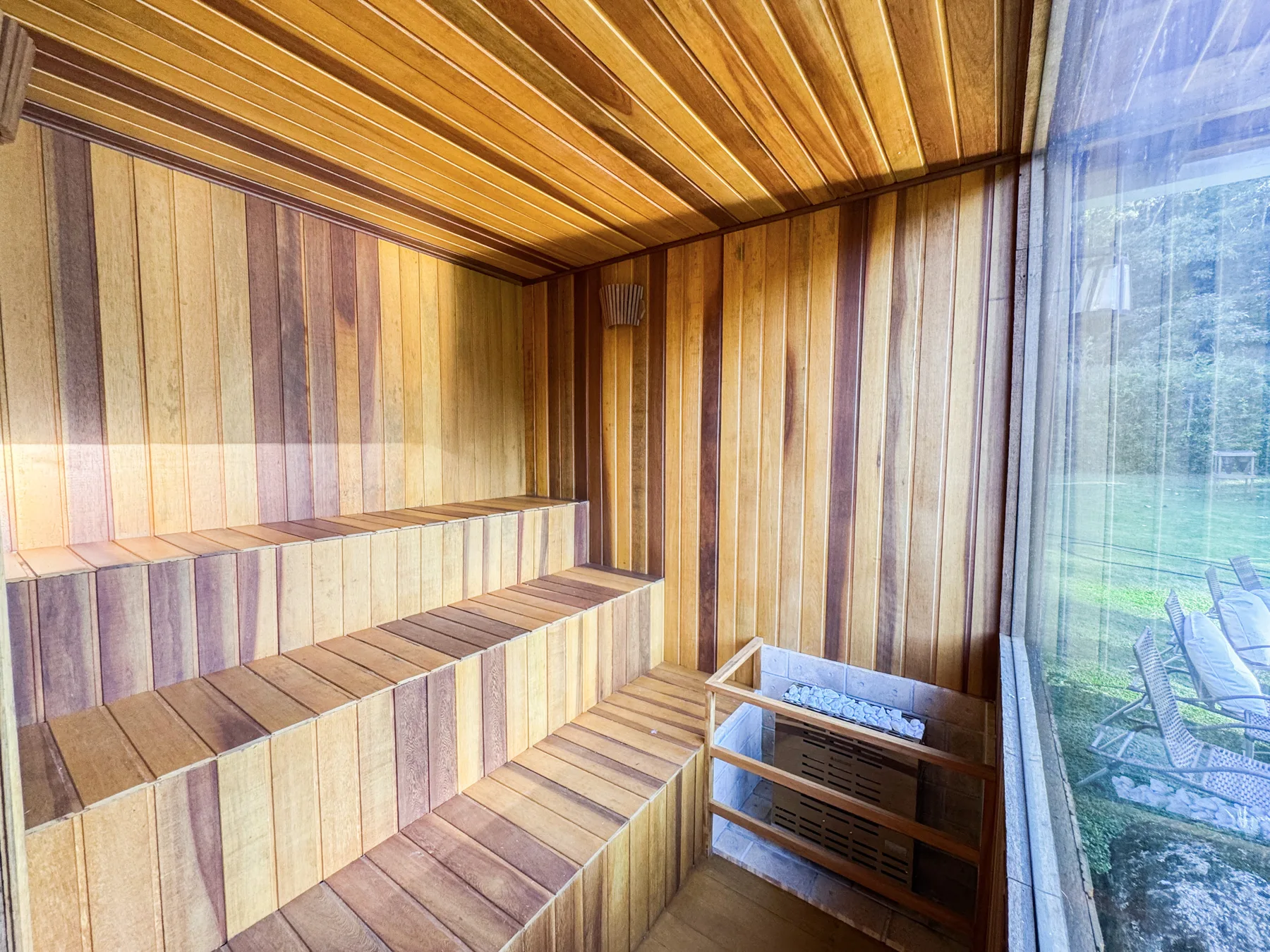 Sauna seca com bancos de madeira e janela voltada para o jardim